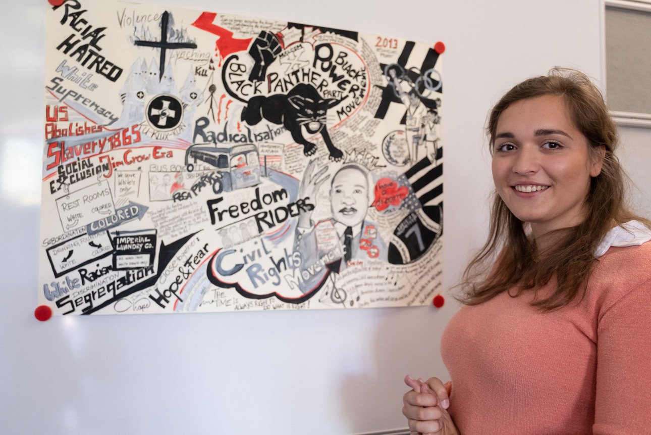 Bild von der Studentin Carla Seitz neben einem selbst gestalteten Plakat zum Thema Schwarze B&uuml;rgerrechtsbewegung 