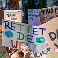 Demonstrierende auf einer Fridays-for-Future-Demonstration halten bunte Schilder für den Klimawandel hoch.