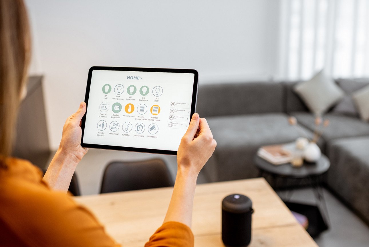 Young woman controlling home with a digital touch screen panel. Concept of a smart home and mobile application for managing smart devices at home