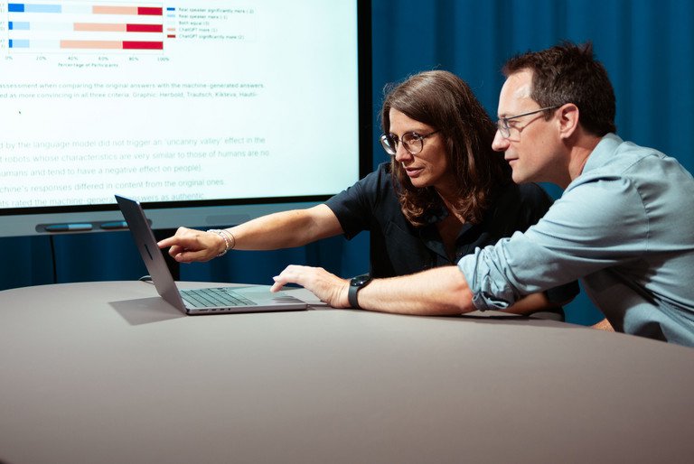 Professors Annette Hautli-Janisz and Steffen Herbold are pointing to a graph showing that the study participants overwhelmingly rated the imitated responses of the AI model as more authentic.