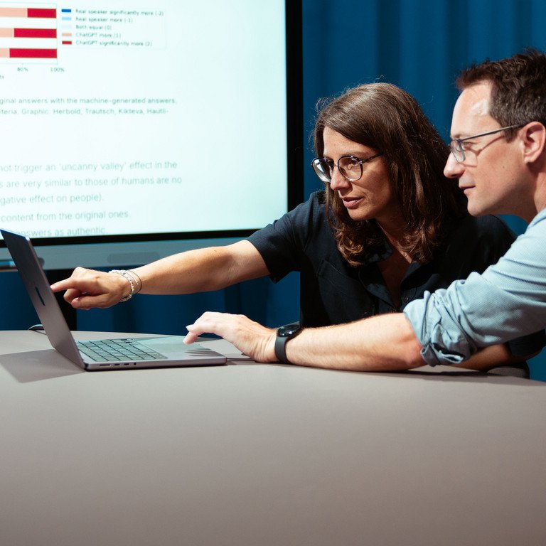 Professors Annette Hautli-Janisz and Steffen Herbold are pointing to a graph showing that the study participants overwhelmingly rated the imitated responses of the AI model as more authentic.