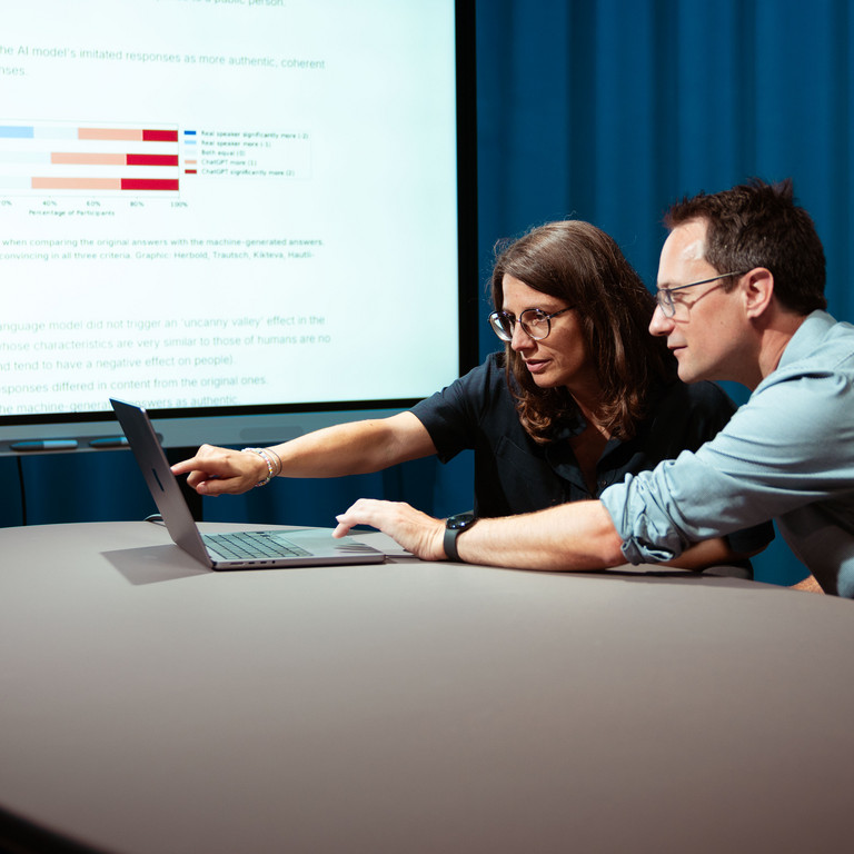 Professors Annette Hautli-Janisz and Steffen Herbold are pointing to a graph showing that the study participants overwhelmingly rated the imitated responses of the AI model as more authentic.