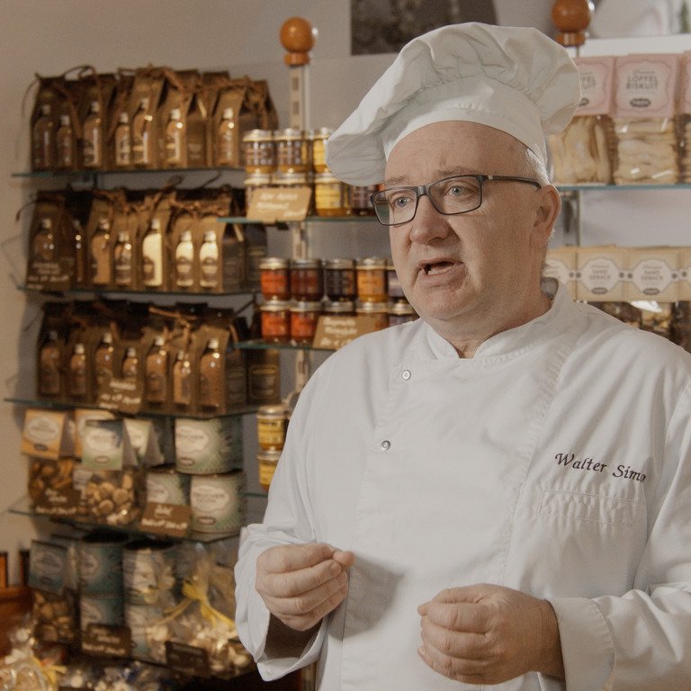 Walter Simon, Inhaber des Caf&eacute;s Simon in der Passauer Innenstadt, steht mit einer B&auml;cker-&auml;hnlichen Arbeitskleidung in seinem Laden.