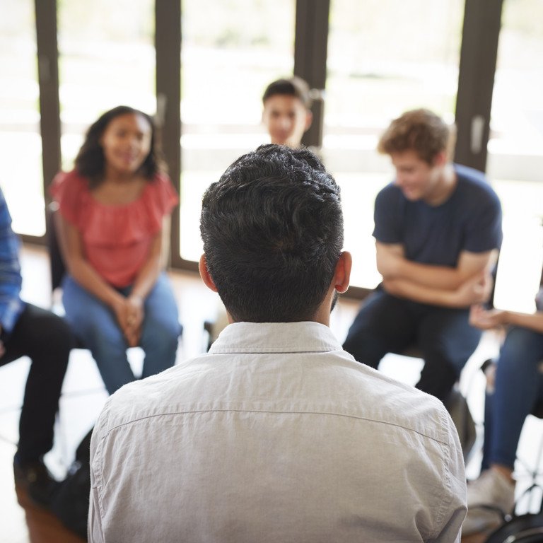 Junge Menschen sitzen in einem Stuhlkreis und unterhalten sich.