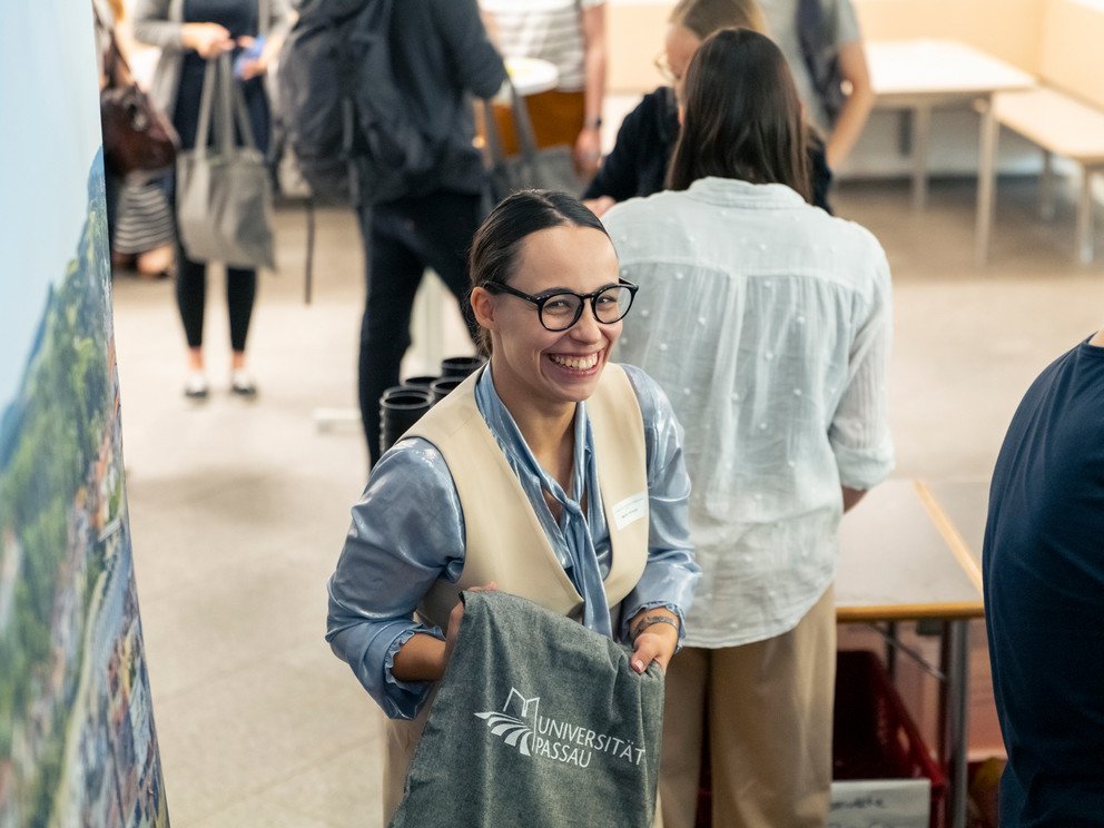 Marie Hirsch von der Professur f&uuml;r Angewandte Ethik an der Universit&auml;t Passau verteilt Programm und Taschen an die Teilnehmenden.