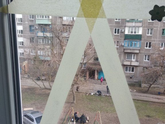 Blick aus dem Fenster der ehemaligen Wohnung von Dr. Melnykova-Kurhanova in Mariupol w&auml;hrend der Belagerung. Zu sehen sind Menschen, die mangels Strom versuchen, drau&szlig;en &uuml;ber offenen Feuer zu kochen. 