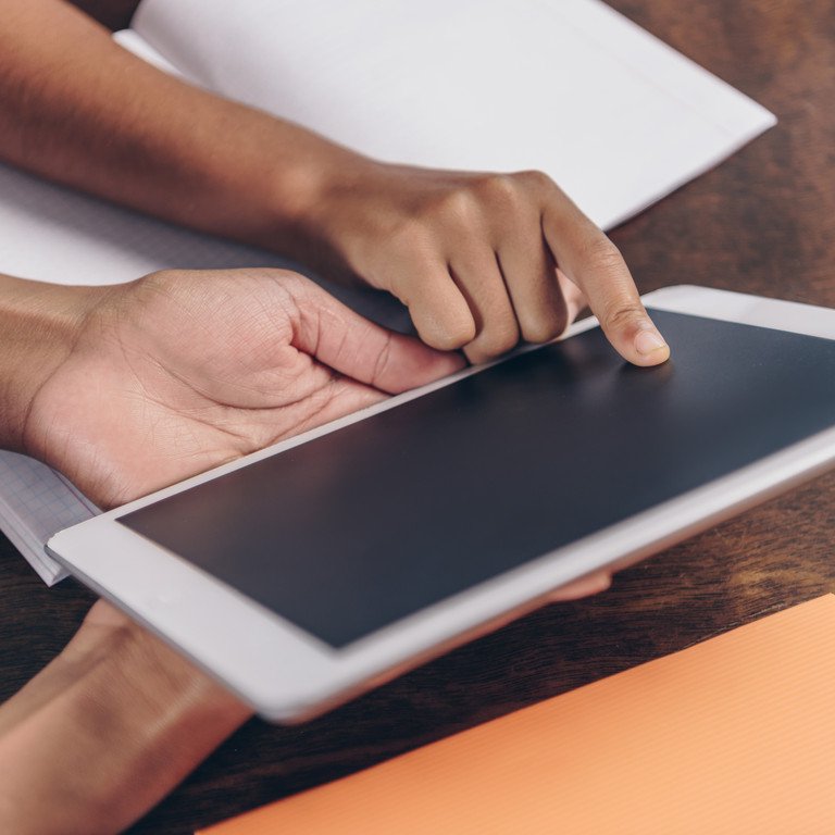 Ein Erwachsener erkl&auml;rt einem Kind etwas auf einem Tablet.