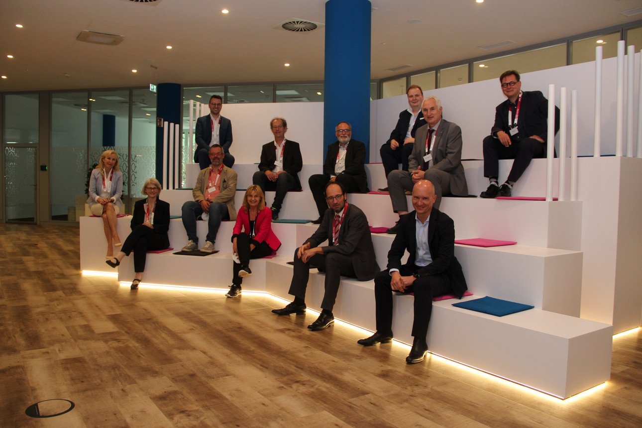 Die Teilnehmenden des Symposiums in M&uuml;nchen konnten nicht nur wertvolle Inputs und Denkanst&ouml;&szlig;e mitnehmen, sondern genossen sichtlich auch den physischen Austausch direkt vor Ort: Dr. Susanne Kl&ouml;pping vom Staatsministerium f&uuml;r Digitales, Dr. Maria Reinisch von der VDW, Vizepr&auml;sident Prof. Dr. Harald Kosch, Philippe Mareine von Atos (1. Reihe v.l.), Vizepr&auml;sidentin Prof. Dr. Christina Hansen, Prof. Dr. Werner Gamerith (2. Reihe v.l.), Prof. Dr. Hermann de Meer, Roland Wossidlo von Atos, Pr&auml;sident Prof. Dr. Ulrich Bartosch (3. Reihe v.l.) sowie Stefan Daller und Dr. Armin Gerl von der Universit&auml;t Passau und Axel Honsdorf vom Bayerisch-Franz&ouml;sischen Hochschulzentrum (4. Reihe v.l.). Foto: Universit&auml;t Passau