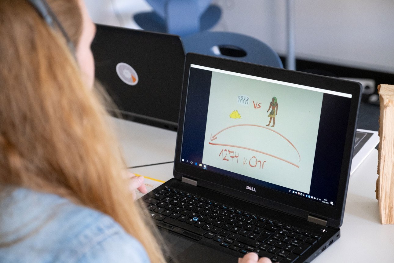 Eine Studentin sitzt vor einem Rechner, auf dem der Anfang des produzierten Legevideos zum Thema Fake News zu sehen ist.